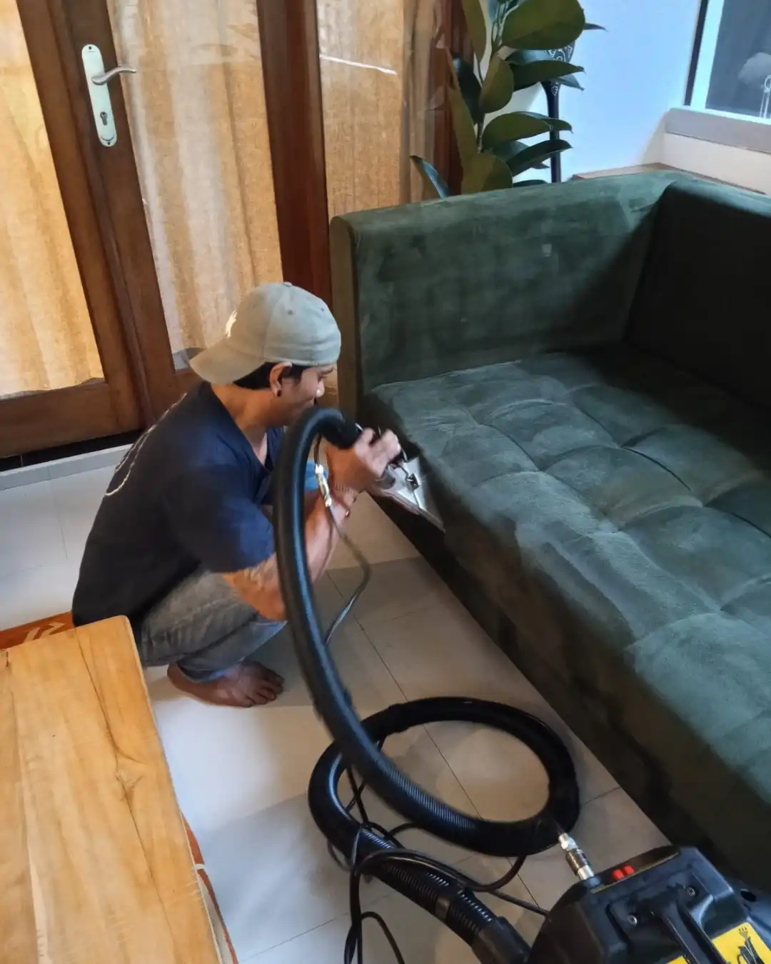 Proclean technician steam cleaning a green fabric sofa in a Hong Kong living room
