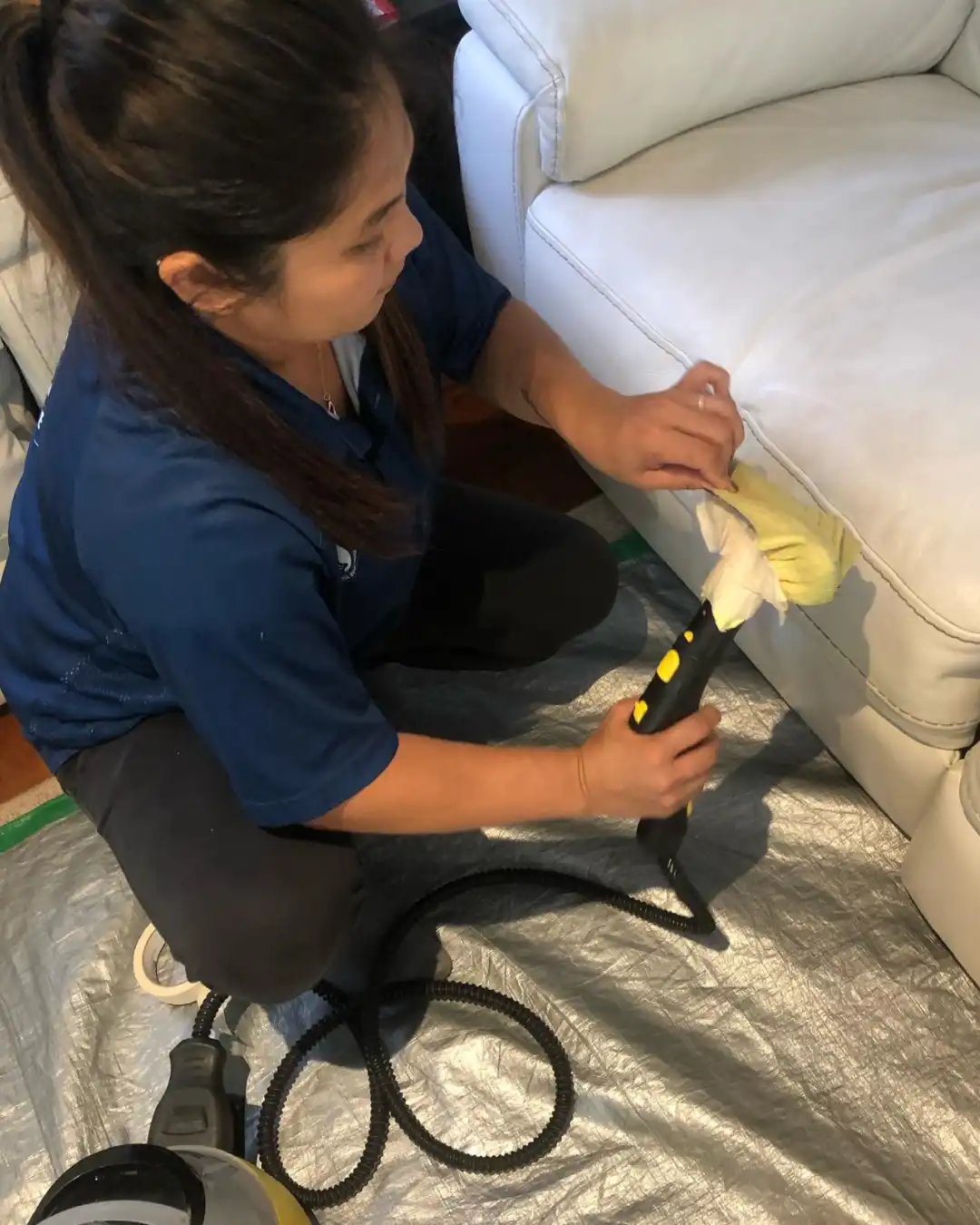 Proclean technician cleaning the seams of a cream leather sofa by hand