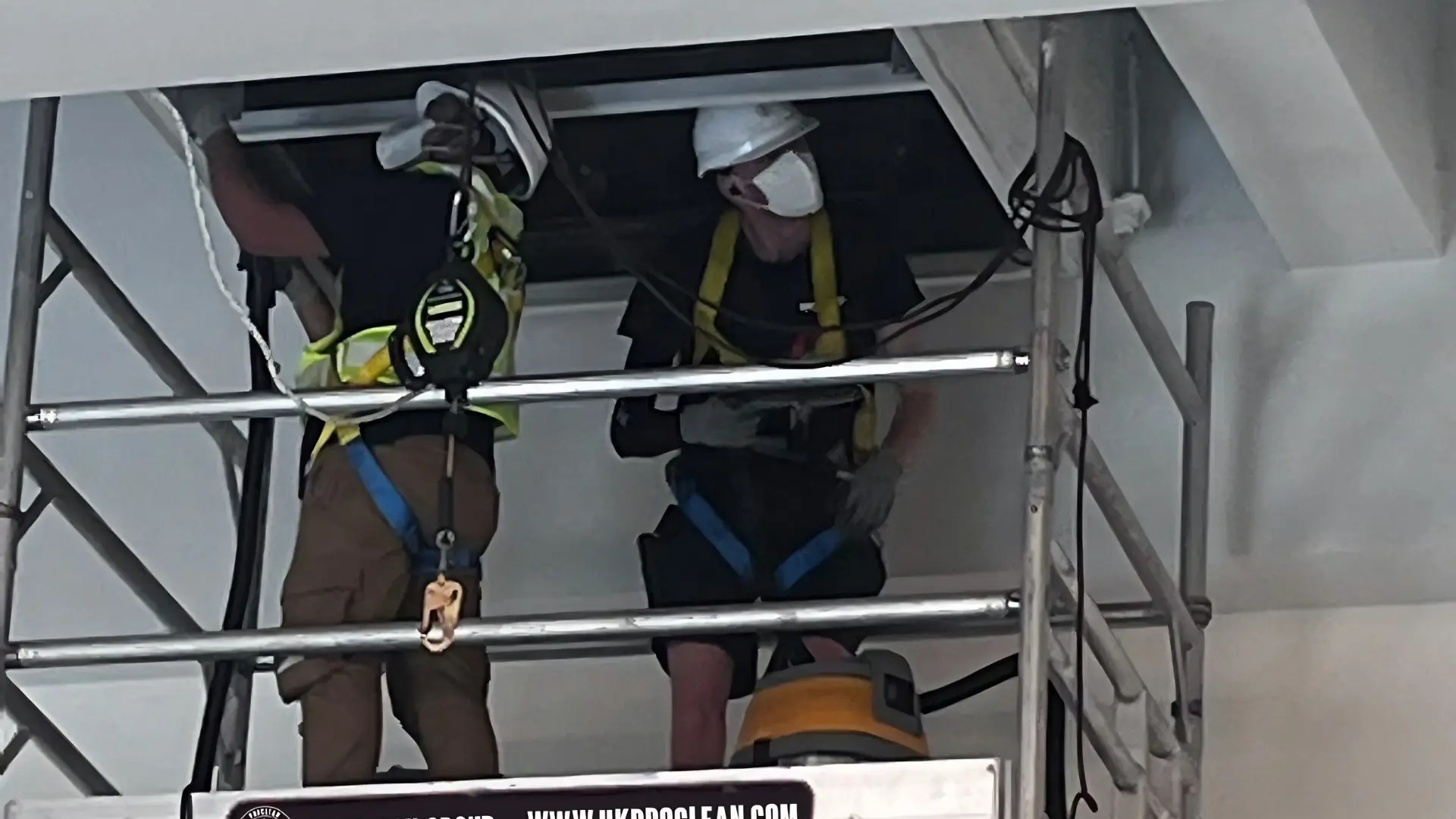 Working at Height: Safe Aircon Servicing in Hong Kong High-Rises 2 Two AirconPro technicians on a scaffold tower cleaning a ducted air conditioning system at ceiling height